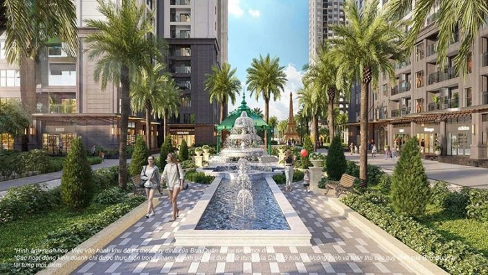 Đường dạo bộ với đài phun nước trung tâm, hàng cọ xanh và các cửa hàng thương mại dưới chân tòa nhà